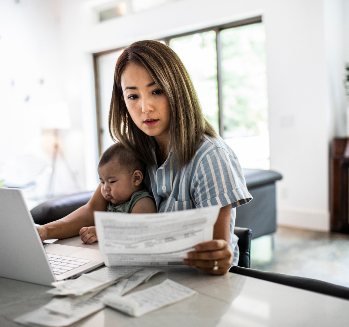 woman reviewing paperwork while holding an infant